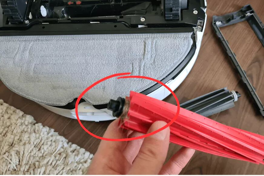 Die festsitzendDie Gummibürste des Roborock S8 Pro Ultra wird in den Händen gehalten und man sieht ganz wenige Haare, die sich um die Bürste gewickelt habenen Haare des Roborock S8 Pro Ultra werden entfernt.